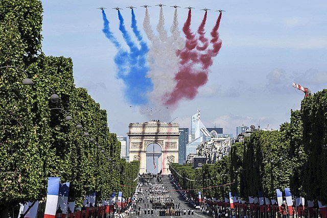 Des militaires américains défilent lors du défilé du 14 juillet 2017 à Paris, sous les traînées de fumée d'un survol effectué par des avions Alpha français